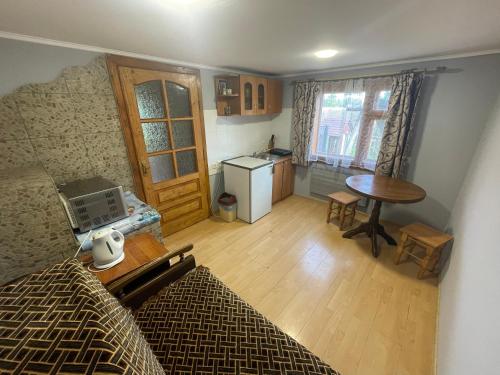 Cette chambre comprend un lit, une table et une cuisine. dans l'établissement Mini Cottage, à Yablunytsya