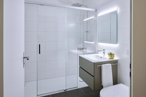 baño blanco con ducha y lavamanos en Lumen Apartments, en Schenkon