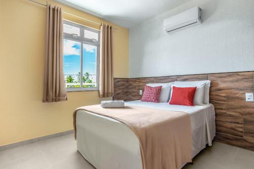 a bedroom with a large bed with red pillows at SAN GIACOMO I Apartamentos por Temporada para amigos, famílias e empresas no Porto das Dunas - Ceará in Aquiraz