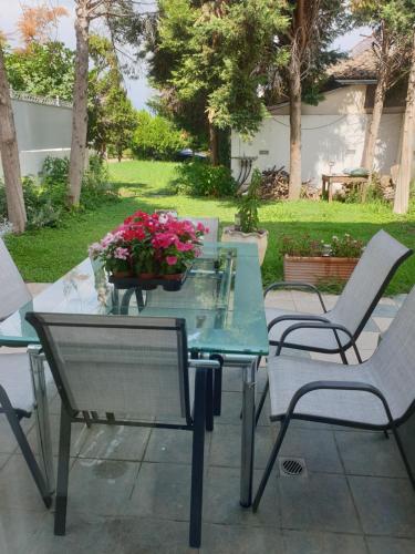 a glass table and chairs with flowers on a patio at HOUSE SUITES DOMAINE in Rizómilos