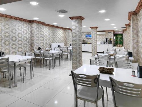 une salle à manger avec des tables et des chaises blanches dans l'établissement DİYAR BUDGET HOTEL, à Istanbul