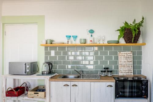 a kitchen with a sink and a microwave at Whale & Tortoise - Lampiesbaai in St Helena Bay