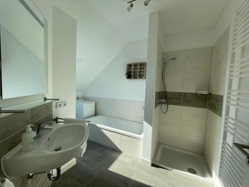 a white bathroom with a sink and a shower at Moderne Wohnung mit Balkon inmitten der Lausitz in Bernsdorf