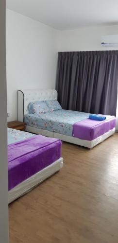 two beds in a room with purple and purple sheets at UMMI GUESTROOM in Kota Bharu