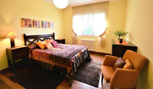 a bedroom with a bed and two chairs and a window at GALIHOST - Finca de Roque in O Grove