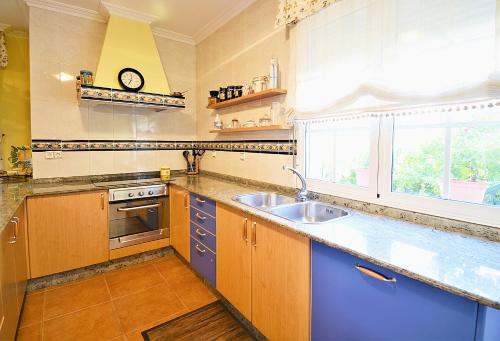 a kitchen with blue cabinets and a sink and a window at GALIHOST - Finca de Roque in O Grove