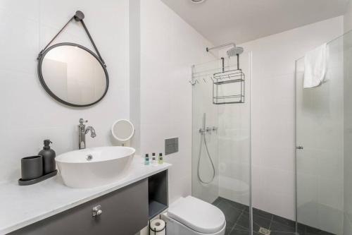 a white bathroom with a sink and a shower at Gordon Area - Amazing one BDR close to the beach in Tel Aviv