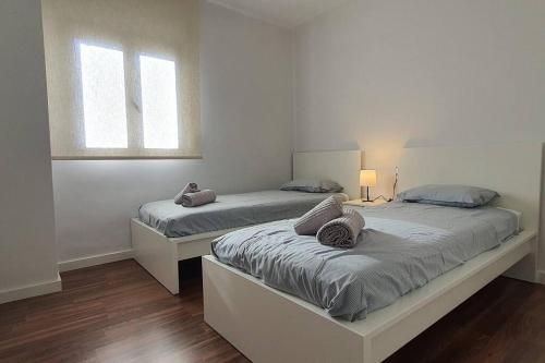 two beds in a white room with two windows at Gran piso en zona comercial Malaga in Málaga