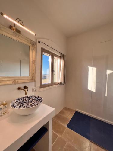 a bathroom with a sink and a glass shower at Masseria Ostuni Mare Agri Resort in Ostuni