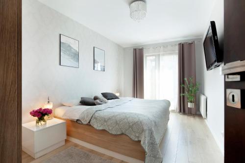 a white bedroom with a bed and a tv at Elite Apartments Waterlane SPA in Gdańsk