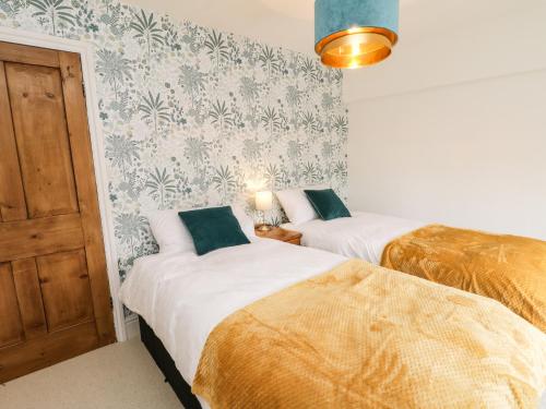 two beds in a room with a door and wallpaper at Cliff House in York