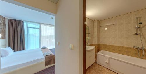 a bathroom with a tub and a toilet and a sink at Hotel Kamenec in Kiten