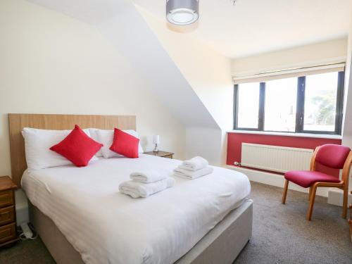 um quarto com uma grande cama branca com almofadas vermelhas em Flat 34 - Marine Court em Littlehampton
