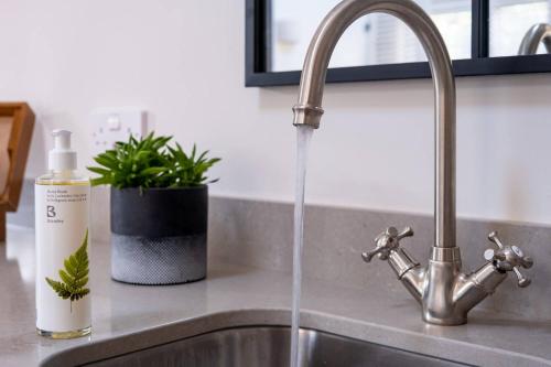 a kitchen sink with water running from a faucet at The Little Gate House in Milford on Sea