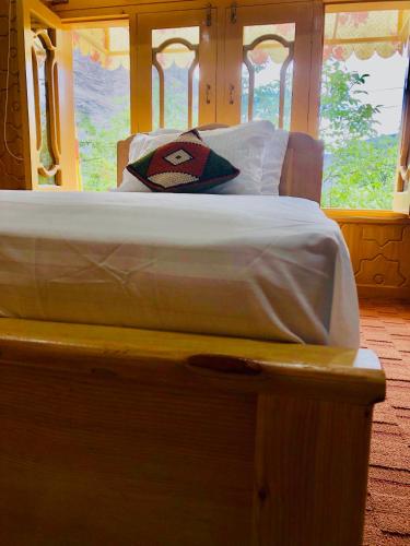 a bedroom with a bed with white sheets and a window at North Palace Khaplu in Khaplu