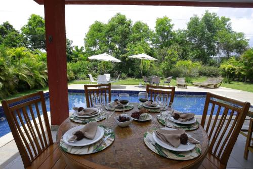 una mesa de madera con platos y sombreros encima en Casa Temporada - 4 suítes - Condomínio Luxo - Piscina Extraordinária - Praia de Itacimirim-BA en Camaçari