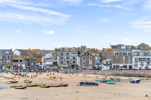 a beach with people and boats on the sand at Tregurno in St Ives