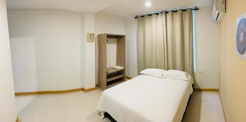 1 dormitorio con cama blanca y espejo en Casa Arena San Andres, en San Andrés