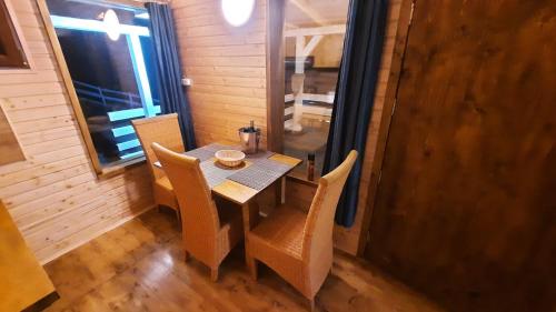 una sala da pranzo con tavolo, sedie e una finestra di Cabana Himalaya Lodge cu ciubăr din inima munților Apuseni- masivul Buces -Vulcan a Buceş-Vulcan