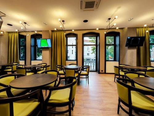 ein Restaurant mit Tischen, gelben Stühlen und Fenstern in der Unterkunft Efbet Hotel in Warna