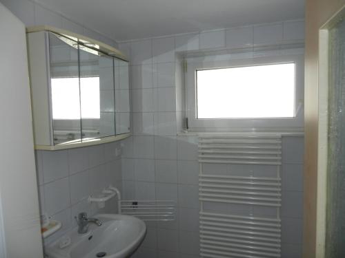 uma casa de banho branca com um lavatório e uma janela em Dachgeschoss Feriewohnung für Zwei em Colônia