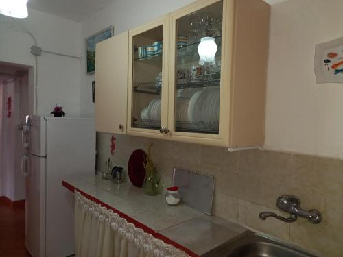 una cocina con fregadero y un armario lleno de platos en Vila Gjoka, en Himare