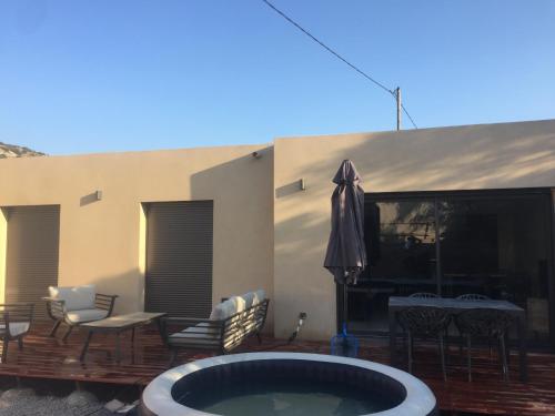 a patio with a hot tub and chairs and a table at Maison neuve 2 min mer in Corbara