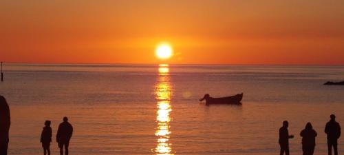 a group of people standing on the beach watching the sunset at The Poplars Guest House in Combe Martin