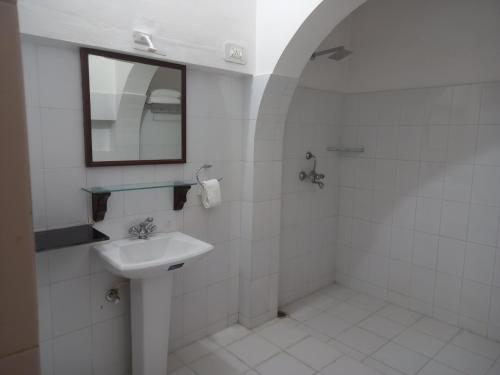 a white bathroom with a sink and a mirror at Sankhu Niwas in Bikaner