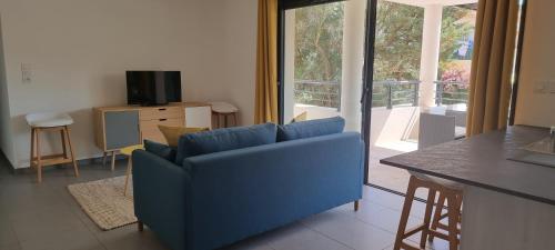 - un canapé bleu dans le salon avec balcon dans l'établissement Appartement T3 proche du Port, à Porto-Vecchio