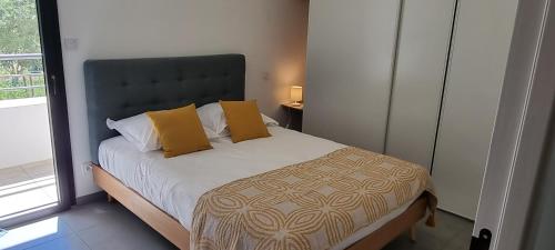 a bedroom with a bed with yellow pillows and a window at Appartement T3 proche du Port in Porto-Vecchio