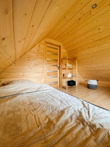 a bedroom with a bed in a wooden room at Chata z Kraja in Pewel Wielka