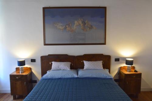 1 dormitorio con 1 cama azul y 2 mesitas de noche en Accogliente locale con terrazzo in centro storico, en Vittorio Veneto