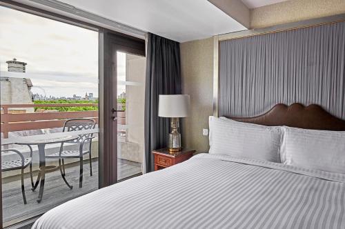 a bedroom with a bed and a balcony with a table at InterContinental London Park Lane by IHG in London