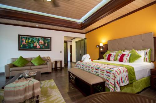 a bedroom with a large bed and a couch at Hotel Arenal Springs Resort & Spa in Fortuna