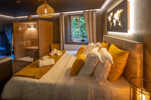 Un dormitorio con una cama grande con almohadas amarillas y blancas en La Suite - Spa & Sauna, en Kaysersberg