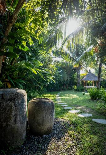 a garden with two large stone pots in the grass at Villa Markisa Echo Beach in Canggu