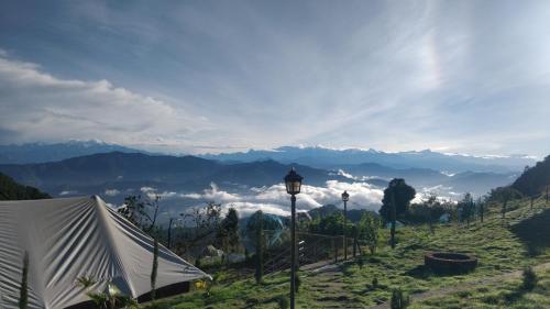 a tent on a hill with a view of mountains at The Bugyal in Kanatal