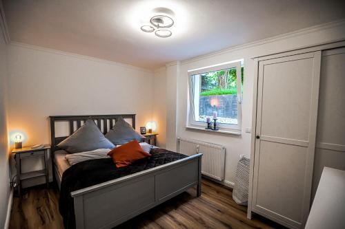een slaapkamer met een bed met een oranje kussen erop bij Exklusive Neubau Wohnung im Luftkurort Buchholz in Buchholz in der Nordheide