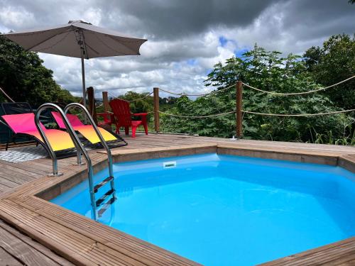 una piscina con sillas y una sombrilla en una terraza en Les Vanniers: Papaye - KARITÉ, en Baie-Mahault