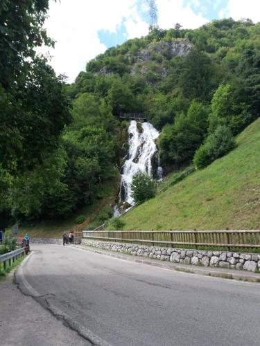 a road with a waterfall on the side of a hill at Appartamento Garda Dolomiti crocevia tra laghi e montagne in Comano Terme