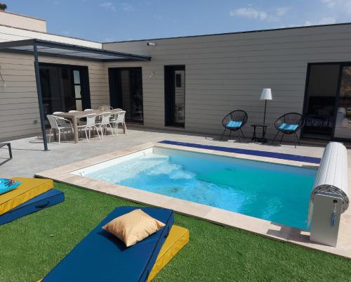 a swimming pool in a yard with chairs and a table at La Belle Vie en Alaric in Douzens