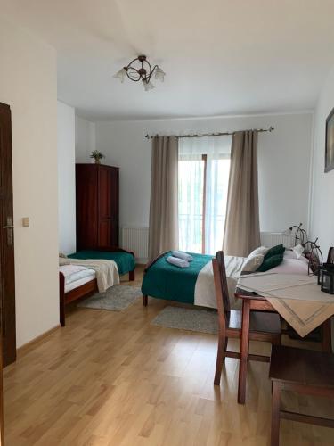 a bedroom with two beds and a table and a window at Pokoje Gościnne U Wioli in Zakopane