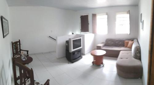 ein Wohnzimmer mit einem Sofa und einem TV in der Unterkunft O Pouso Sobrado in Mucugê