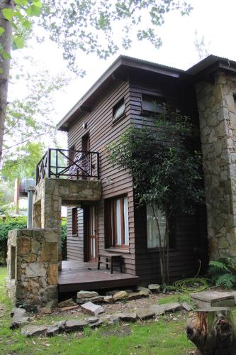 uma pequena casa com um alpendre e um deque em Cabañas Las Olivas em Mar del Plata