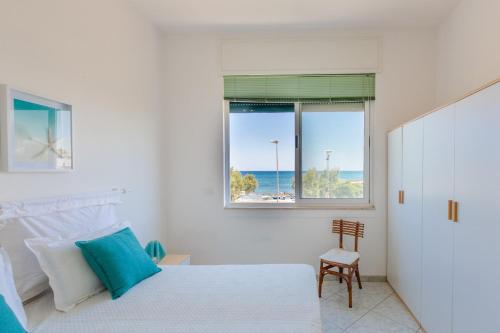 Un dormitorio con una cama y una ventana y una silla. en La vista mare da Rossella, en Specchiolla