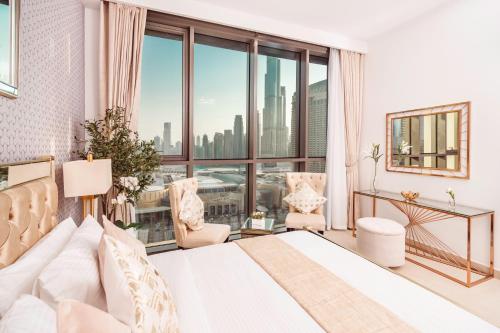 ein Schlafzimmer mit einem weißen Bett und einem großen Fenster in der Unterkunft Elite Royal Apartment - Panoramic Full Burj Khalifa, Fountain & Skyline View - ACed direct connection to Dubai Mall - Governor in Dubai