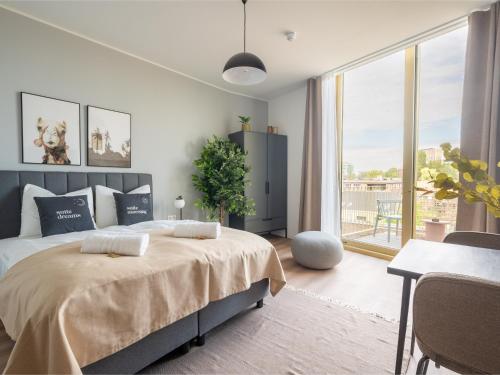 a bedroom with a bed and a table and a window at Limehome Eindhoven Gashouder in Eindhoven