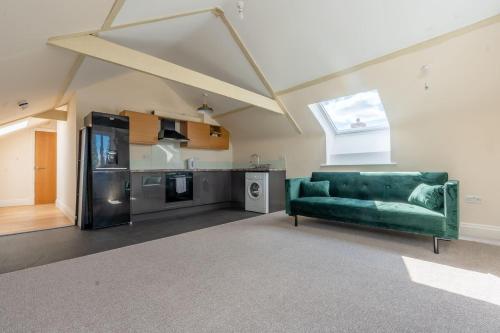 a living room with a green couch and a kitchen at Charming 1-Bed loft in Caerleon in Newport