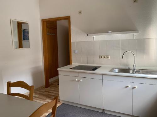 eine Küche mit weißen Schränken, einer Spüle und einem Tisch in der Unterkunft Hotel am Freihafen in Duisburg